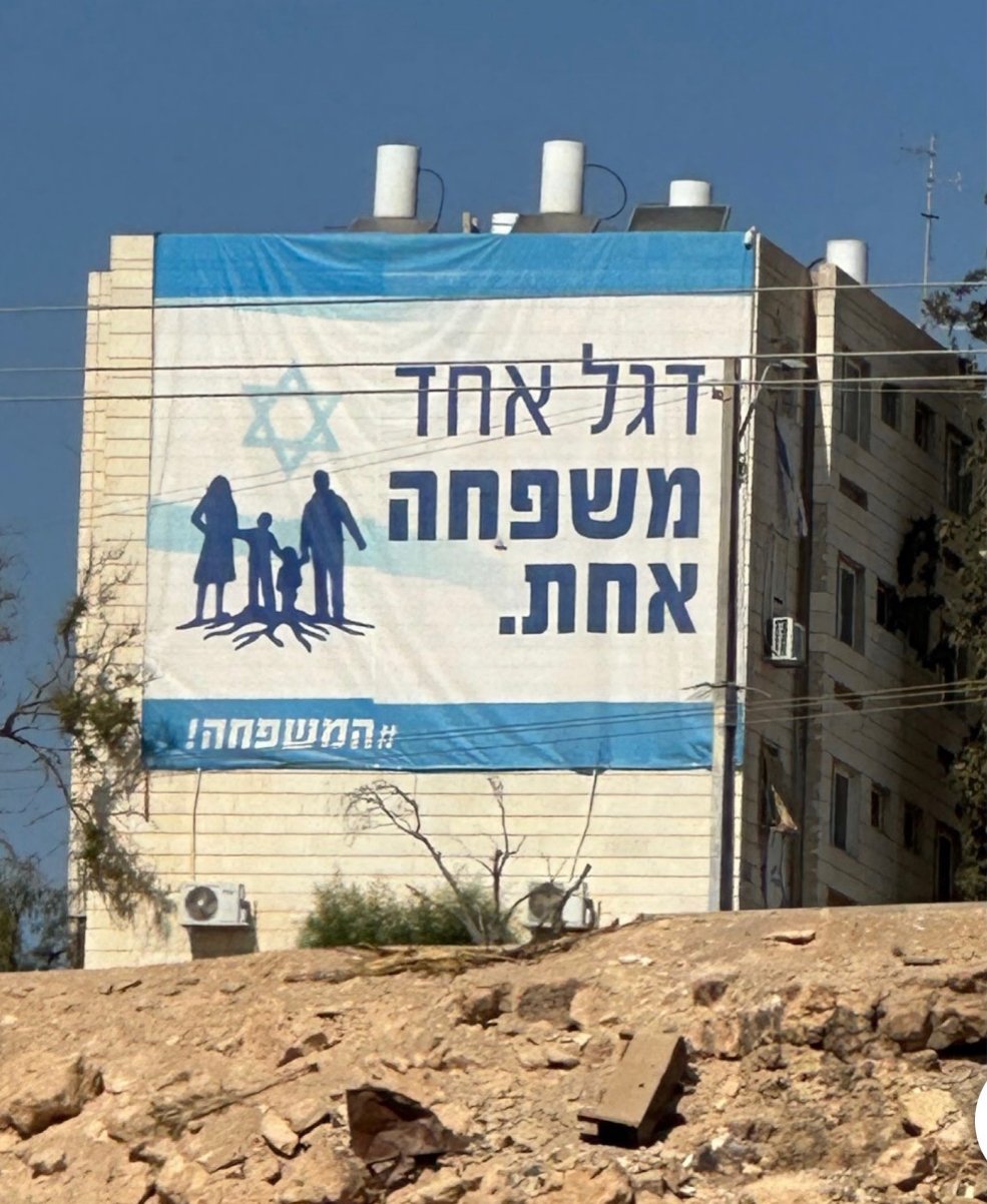 Image illustrating the phrase "one flag, one family" on the side of a school building at Kibbutz Erez